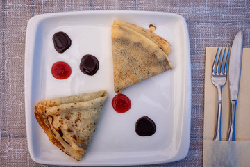 Pancakes on the white plate with jam and chocolate, served dish for breakfast