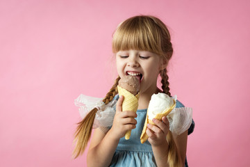little girl with pigtails in a blue dress eating ice cream in a cone on a pink background
