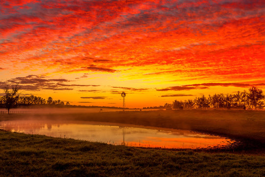 Blazing red sunrise skies across rural landscape Australia - Powered by Adobe