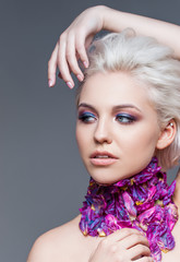 Naklejka premium Woman with trendy make up smoky eyes . Short clarified hairs, with violet petals of a tulip on her neck. Grey background