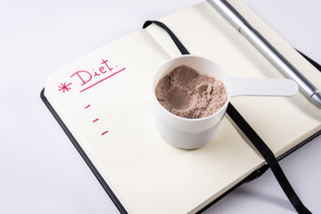 Measuring scoop of whey protein and notebook for diet. Concept of diet, health and exercise
