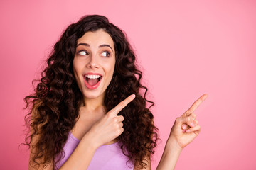 Obraz premium Photo of cheerful funky funny crazy nice glad sweet attractive girl pointing at emptiness away from her surprisingly while isolated with pink background