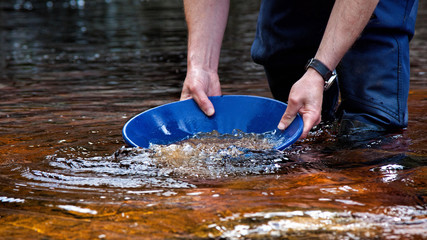 Man in a dry suit gold panning in the Kildonan Burn for gold