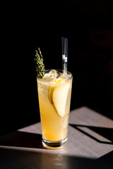 A glass of pear lemonade on an iron table with amazing light and deep black background.