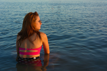 young redhead woman sitting in front of the sea