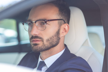 Handsome bearded businessman sitting in white car salon