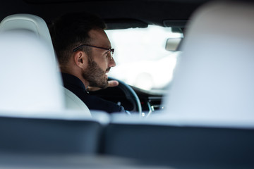 Bearded man looking into side mirror while driving responsibly