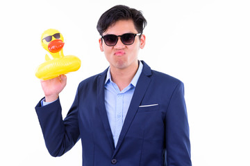 Young handsome Asian businessman with sunglasses holding inflatable duck