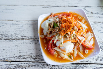 green papaya salad in white plate on wooden background
