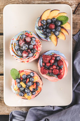 Desserts berry cakes with various berries: red and black currants, blueberries, raspberries, peaches with almonds. Top view