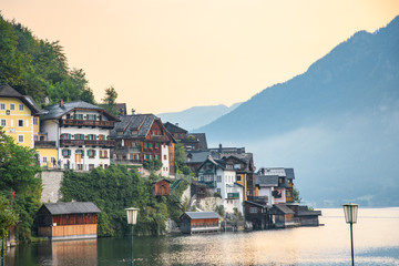 Fototapeta na wymiar View of a mountainous Austrian village on the shore of an alpine lake on a background of mountains in the rays of the setting sun. Hallstatt. Hallstattersee. Austria.