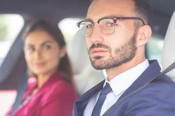 Bearded young man wearing glasses sitting near wife in car