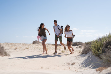 Fototapeta premium Three young people running on the beach