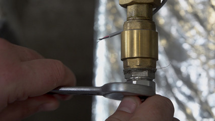 Plumber unscrews a wrench unscrews a nut on a water pipe