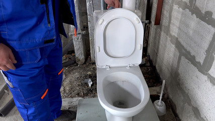Plumber checks the operation of the toilet, drains the water in the toilet