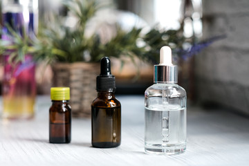 Brown, clear glasses with dropper, organic green leaves on dark background. Serum or essential oil with herbal extract