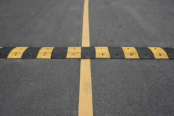 Yellow paint line and speed bump line on asphalt road
