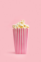 Caja de Popcorn palomitas de maíz sobre un fondo rosa pastel liso y aislado. Vista de frente y de...
