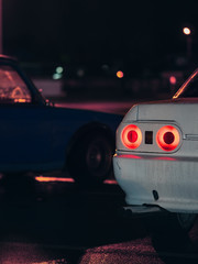Close-up of the back of an old sports drift car with red taillights at night on the road