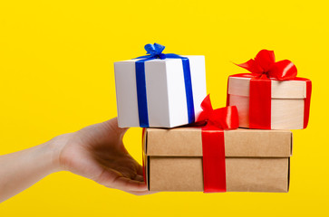 Gift boxes with ribbon in hand on yellow background