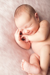 Smiling newborn baby girl sleeping on pink bean bag.