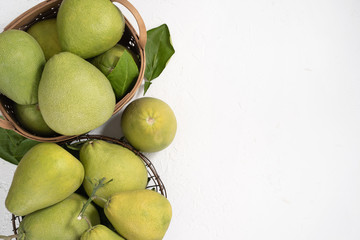 Fresh pomelo, grapefruit in bamboo basket with green leaf on bright white background. Seasonal fruit for Mid-Autumn Festival. Top view. Flat lay.