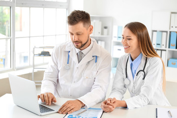 Male and female doctors working at table in clinic