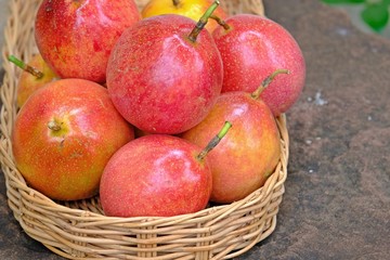 Many passion fruits in bamboo basket placed on stone table.