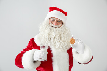 Obraz na płótnie Canvas Portrait of Santa Claus with milk and cookie on light background