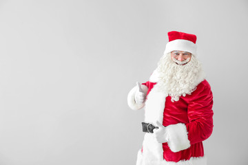 Portrait of Santa Claus showing thumb-up on light background