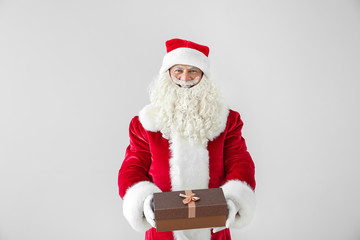 Portrait of Santa Claus with gift on light background