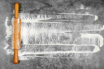 Rolling pin and white flour on a gray background. Free space for text . Flat lay, top view, copy space for your text.