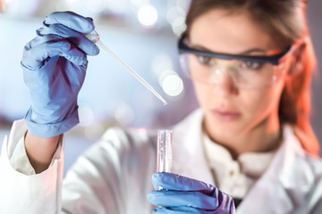 Life scientists researching in laboratory. Focused female life science professional pipetting...