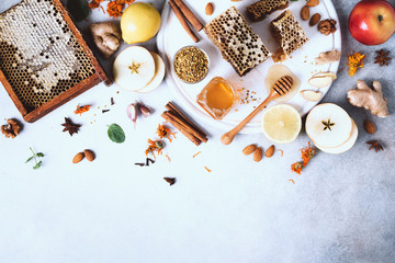 Fototapeta na wymiar Autumn picnic. Herbal tea, honey and bee products, apple, lemon, calendula, spices on grey concrete background. Immune system support with alternative medicine. Top view, copy space