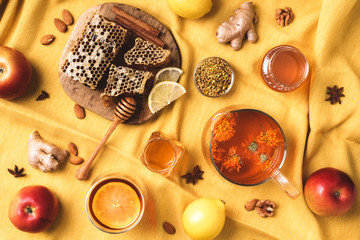 Autumn harvest concept. Set of honey and bee products, apple, lemon, calendula tea, spices on yellow background. Immune system support with alternative medicine - obrazy, fototapety, plakaty