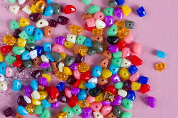 Multicolored beads for needlework on a pink background