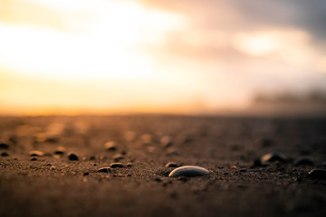 Dramatic sunset over a black sand beach with pebbles, Bali, Indonesia