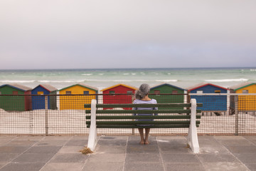 Senior woman sitting on promenade bench at beach