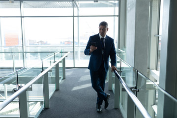 Front view of businessman leaned on the railing and using his mobile phone 