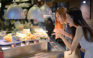 women exciting to having meals in food court of the shopping mall