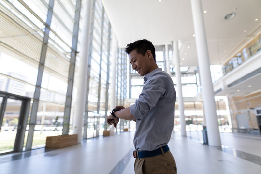 Asian male executive using smartwatch in modern office