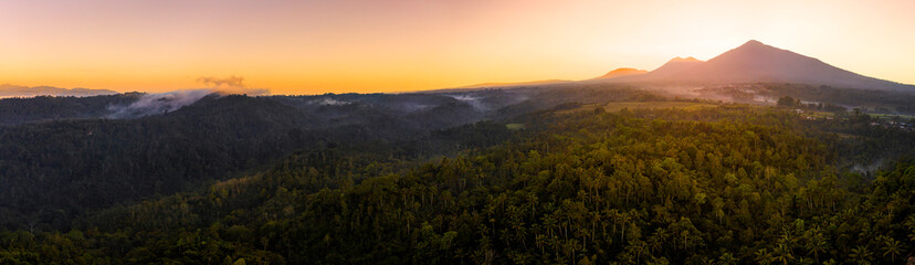 Mount Agung volcano surrounded by dense rainforest with a dramatic sunrise panoramic, Bali, Indonesia