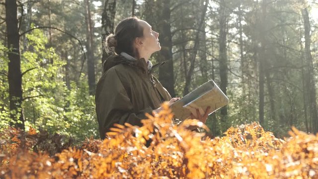 Woman lost in the forest, looking at old map, thinking, nature background, concept: search for yourself. Woman with map in forest. Young beautiful woman hiking on a forest. Closeup portrait shot 4k