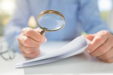 Businessman with magnifying glass reading documents