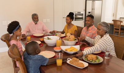 Multi-generation family praying together before having meal