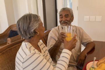 Senior couple toasting glasses of orange juice