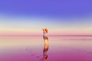 The girl in the pink lake. Unreal landscape at sunset.