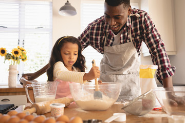 African American father and daughter baking cookies in kitchen
