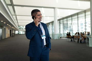 Fototapeta premium Businessman calling someone on mobile phone and looking away in office lobby