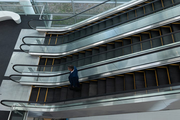 Caucasian businessman talking on mobile phone while moving down on escalator